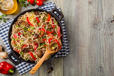 Sığır etli Çin makarnası. Tavada hazır. Ahşap arka plan. Üst görünüm.