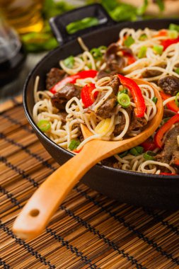 Sığır etli Çin makarnası. Tavada hazır. Ahşap arka plan. Ön görünüm.