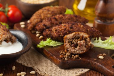 Geleneksel Arap kibbesi, kuzu ve çam fıstığı. Ön manzara. Doğal ahşap zemin.