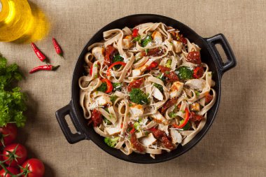 Kızarmış tavuk, kurutulmuş domates ve brokoli ile tam tahıllı tagliatelle makarna. Bir kanepede hizmet etti. Üst görünüm.