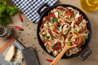 Kızarmış tavuk, kurutulmuş domates ve brokoli ile tam tahıllı tagliatelle makarna. Bir kanepede hizmet etti. Üst görünüm.
