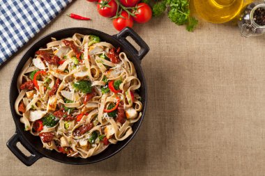 Kızarmış tavuk, kurutulmuş domates ve brokoli ile tam tahıllı tagliatelle makarna. Bir kanepede hizmet etti. Üst görünüm.