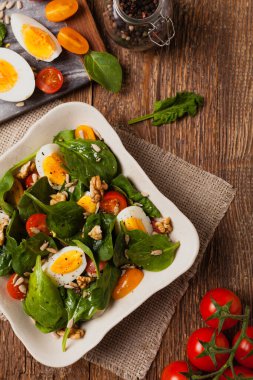 Lezzetli ıspanak salatası, haşlanmış yumurta, domates, fındık ve ayçiçeği çekirdeği. Üst görünüm.