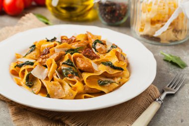 İtalyan salatası, pappardelle makarna, ıspanak, ızgara tavuk ve kurutulmuş domates, üzerine peynir serpiştirilmiş. Ön manzara. Taş arkaplan.