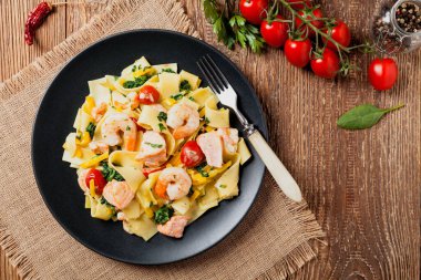 Geleneksel İtalyan fettuccini ile somon, karides ve ıspanak. Doğal tahta arka plan. Üst görünüm.