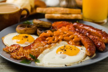 Tam İngiliz kahvaltısı, sosis, mantar, fasulye ve sahanda yumurta. Ön görünüm. 