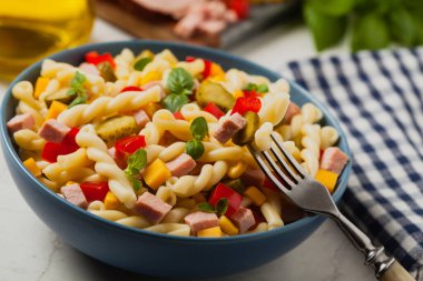 Jambon ve sebzeli salatalı İtalyan fusilli makarna. Ön manzara. Arkaplan beyaz taşı