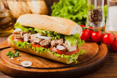 Lezzetli ton balıklı sandviç, marul, domates ve soğanlı. Arka planda doğal ahşap. Ön görünüm.