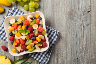 Taze meyveli lezzetli meyve salatası. Arkadaki tahta, gri masa. Üst görünüm.
