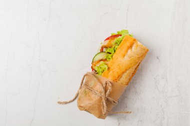 Domatesli tavuklu sandviç, salatalık, marul ve soğanlı. Beyaz taş arka plan. Üst Manzara. Düz yatıyordu.