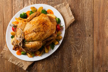 Kızarmış tavuk bütünü. Sebze ve fırında patatesle servis edilmiş. Düz yatıyordu. Üst görünüm. 