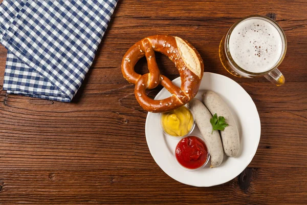 Boiled white sausages, served with beer and pretzels. Perfect for Octoberfest. Natural wooden background. Top view.