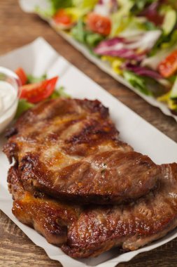 Hazır ol. Kızarmış domuz boynu, patates kızartması, ekmek ve salata ile servis edilir, kağıt tepsilerde servis edilir. Ön görünüm.