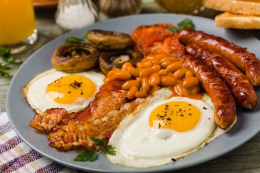 Tam İngiliz kahvaltısı, sosis, mantar, fasulye ve sahanda yumurta. Ön görünüm. 
