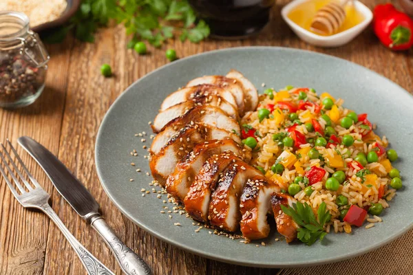 Teriyaki soslu ızgara tavuk göğsü. Kahverengi pirinç ve sebzelerle servis edilir. Ön görünüm. 