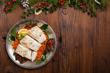 Noel balığı. Kızarmış morina parçaları, sebze sosunda servis edilir. Xmas stili. Üst görünüm.