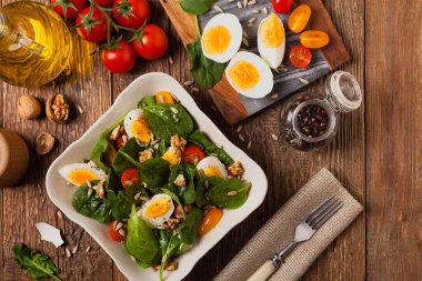 Lezzetli ıspanak salatası, haşlanmış yumurta, domates, fındık ve ayçiçeği çekirdeği. Üst görünüm.