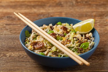 Kızarmış dana eti, pilav, Çin lahanası ve mantar. Susam ve soya sosu serpilmiş. Ön görünüm. 