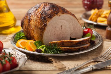 Fırında jambon, eski bir tabakta servis edilir. Doğal ahşap arka plan. Ön görünüm.