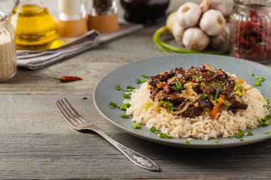 Geleneksel Kore Bulgogi yemeği. İnce dilimlenmiş, ızgara sığır eti, pirinç ve sebzelerle servis edilmiş. Ön manzara. Doğal ahşap zemin.