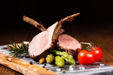 Fırında kuzu fileto, kuşkonmazla servis edilir. Koyu arkaplan.