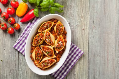 Kuru domates ve etle doldurulmuş İtalyan Conchiglioni Rigati makarnası. Peynir serpilmiş. Üst görünüm.