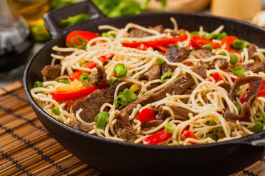 Sığır etli Çin makarnası. Tavada hazır. Ahşap arka plan. Ön görünüm.