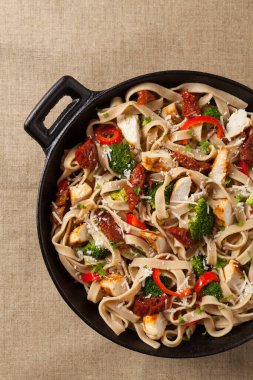 Kızarmış tavuk, kurutulmuş domates ve brokoli ile tam tahıllı tagliatelle makarna. Bir kanepede hizmet etti. Üst görünüm.