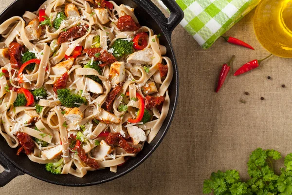 Kızarmış tavuk, kurutulmuş domates ve brokoli ile tam tahıllı tagliatelle makarna. Bir kanepede hizmet etti. Üst görünüm.