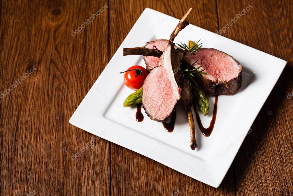 Baked lamb loin, served with asparagus. Dark background.