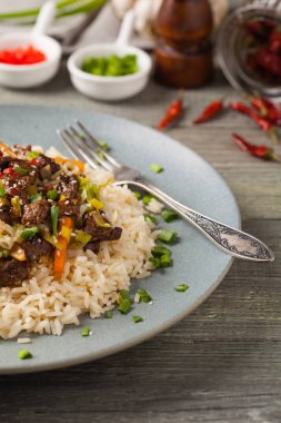 Geleneksel Kore Bulgogi yemeği. İnce dilimlenmiş, ızgara sığır eti, pirinç ve sebzelerle servis edilmiş. Ön manzara. Doğal ahşap zemin.