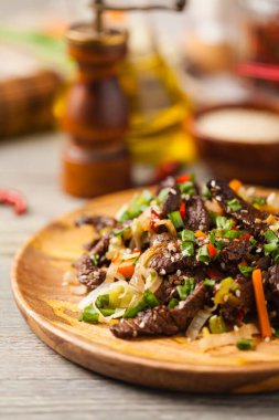 Geleneksel Kore Bulgogi yemeği. İnce dilimlenmiş, ızgara sığır eti, pirinç ve sebzelerle servis edilmiş. Ön manzara. Doğal ahşap zemin.