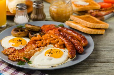 Tam İngiliz kahvaltısı, sosis, mantar, fasulye ve sahanda yumurta. Ön görünüm. 