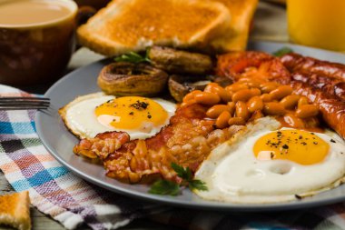 Tam İngiliz kahvaltısı, sosis, mantar, fasulye ve sahanda yumurta. Ön görünüm. 