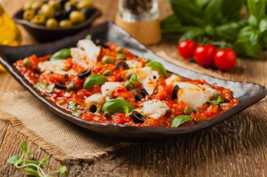 İtalyan usulü morina, domatesli zeytin ve kapari. Ön görünüm.