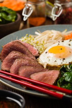 Lahanalı Kore bifteği, ıspanak ve kızarmış yumurta. Ön görünüm.