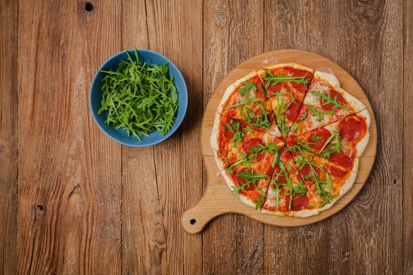 ルコラと木製のボード上のピザペパロニを食べる準備ができて 最上階だ コンセプト — ストック写真