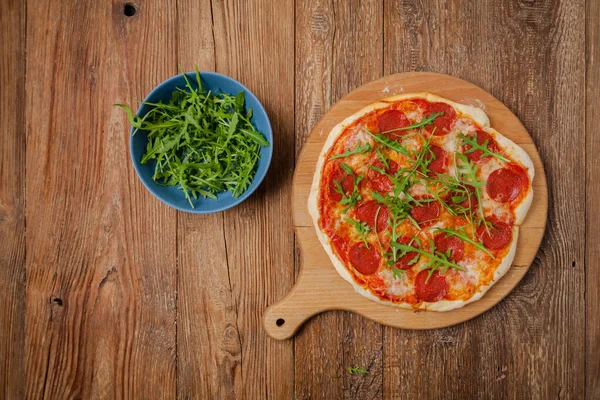ルコラと木製のボード上のピザペパロニを食べる準備ができて 最上階だ コンセプト — ストック写真