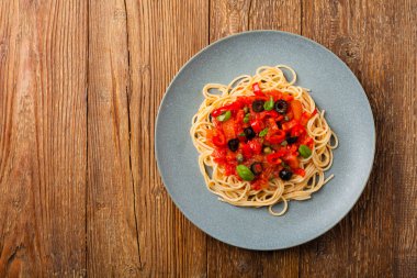 Domates ve zeytinli İtalyan spagetti alla Pultanesca. Et ve peynir olmadan servis edilir. Üst Manzara. Doğal ahşap zemin. 