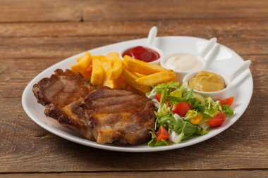 Kızarmış domuz boynu, patates kızartması ve salatayla servis ediliyor. Ön görünüm. 