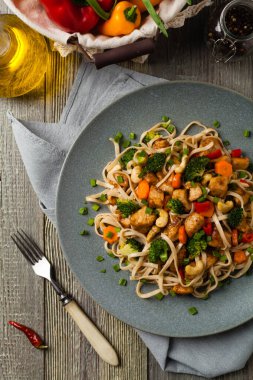 Tavuk, brokoli ve havuçla karıştırılmış makarna. Üst Manzara. Gri ahşap arka plan. Gri bir tabakta servis edilir..