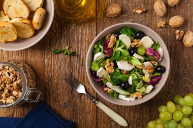 Keçi peynirli, üzümlü ve cevizli İtalyan bahar salatası. Kızarmış ekmekle servis edilir. Üst görünüm. 