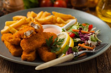 Patates kızartmalı balık ve gri tabakta salata. Ön görünüm.