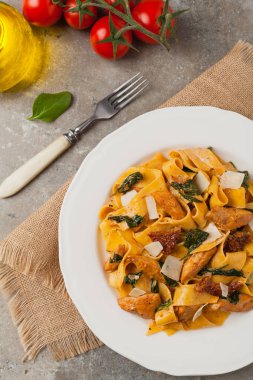 İtalyan salatası, pappardelle makarna, ıspanak, ızgara tavuk ve kurutulmuş domates, üzerine peynir serpiştirilmiş. Üst Manzara. Taş arkaplan.