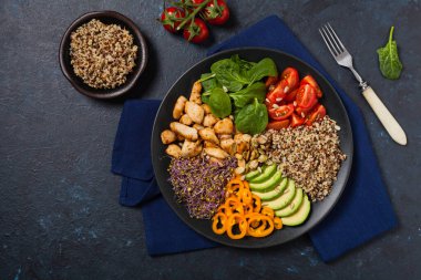 Kinoalı salata, avokado ve tavuk. Üst Manzara. Siyah bir tabakta servis edildi..