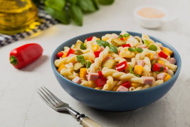 Jambon ve sebzeli salatalı İtalyan fusilli makarna. Ön manzara. Arkaplan beyaz taşı