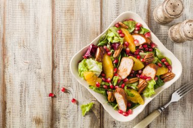 Tavuk, nar, portakal, fındık ve bal ile bahar salatası. Eski masa arkaplanı. Üst Manzara. Ahşap masa arkaplanı. 