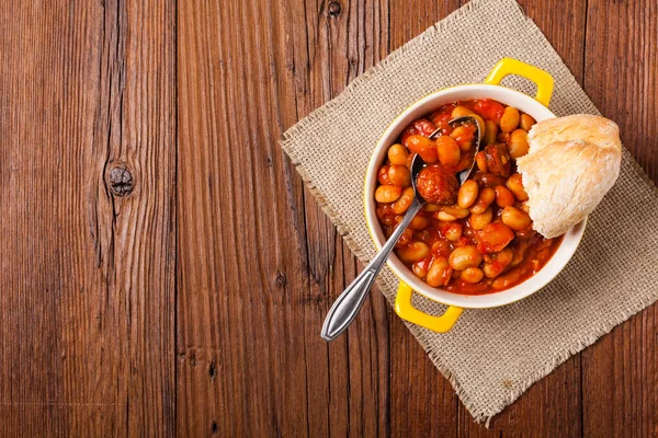 Baked beans in tomato sauce served in yellow, clay bowls. Top view.