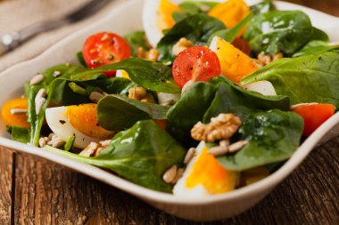 Lezzetli ıspanak salatası, haşlanmış yumurta, domates, fındık ve ayçiçeği çekirdeği. Ön görünüm.