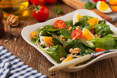 Lezzetli ıspanak salatası, haşlanmış yumurta, domates, fındık ve ayçiçeği çekirdeği. Ön görünüm.